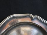 a silver plate on a black table with a black background