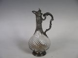 an antique silver plated glass pitcher on a stand on a white background