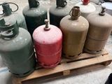 Plusieurs bouteilles de gaz propane sont empilées sur une palette dans un entrepôt