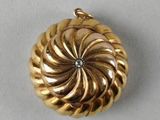 a close up of a gold pendant with a diamond in the center