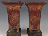 une paire de vases rouges et dorés posés sur un socle en bois
