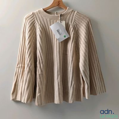 un pull suspendu à un cintre, avec une étiquette dessus