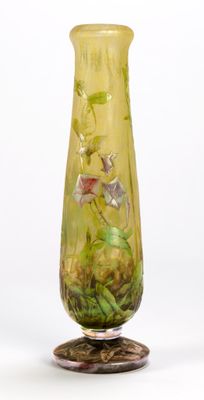 a yellow vase with flowers on it sitting on a stand