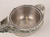 a silver bowl with a bird on it on a white surface