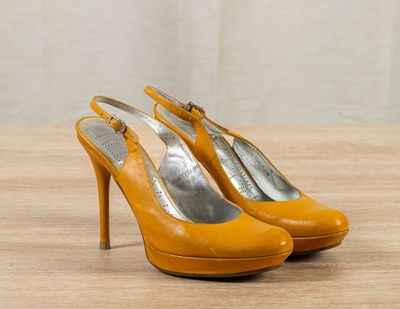 an image of a pair of yellow high heel shoes on a wooden table