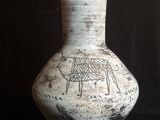 un vase blanc orné d'un motif sur un fond noir