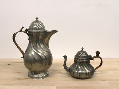 une cafetière et une théière plaquées argent posées sur une table en bois