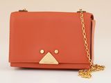 an orange purse with a gold triangle on the front and a chain around it