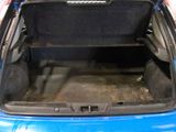 the back of a blue car with its trunk open in a garage