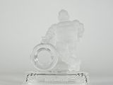 figurine en verre transparent représentant un homme tenant une bague, posée sur un socle