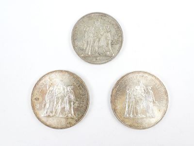 trois pièces d'argent posées l'une sur l'autre sur une surface blanche