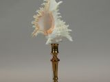 a gold vase with a white shell on top of it