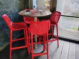 a red table and chairs in front of a large window
