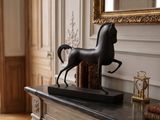une statue de cheval posée sur une cheminée dans une pièce