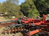 an old red tractor plow sitting in the middle of a field