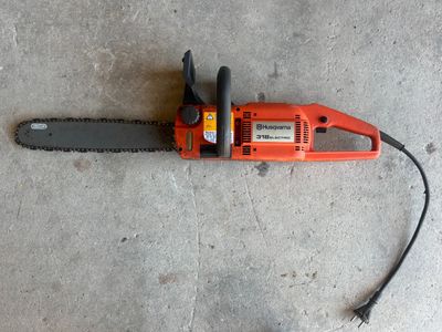 an orange chainsaw laying on the ground on a concrete floor