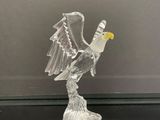 figurine en verre représentant un oiseau aux ailes déployées, posée sur un fond noir