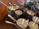 a lot of silver cups and spoons sitting on a table