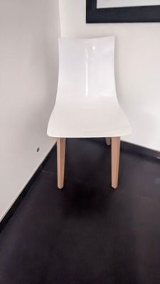 une chaise blanche posée dans un coin d'une pièce