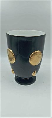 une tasse noire et dorée, parsemée de petits points dorés