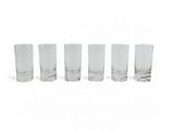 quatre verres transparents sont alignés sur une surface blanche