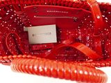 a red handbag with a phone in it on a white surface