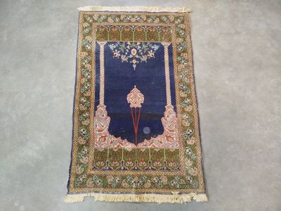 un tapis oriental à fond bleu et bordure dorée posé sur un sol gris