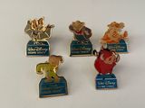 Quatre pin's Disney sont posés sur une surface blanche