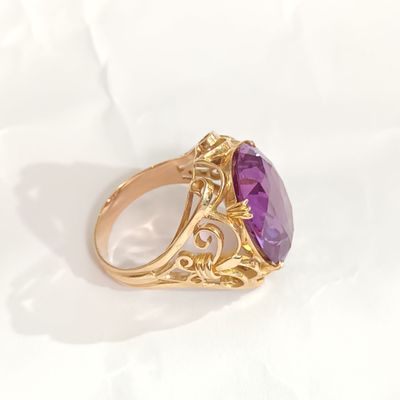 gros plan d'une bague en or avec une pierre violette