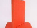 two orange books stacked on top of each other on a white surface
