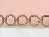 four gold rings on a marble table against a pink background