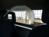 a giraffe behind a fence in the back of a car