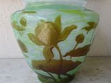 a green vase with a flower on it on a table