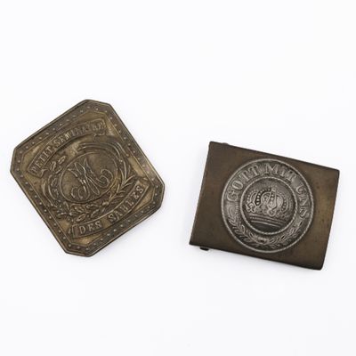 deux boutons anciens en métal et une pièce de monnaie posés sur une surface blanche