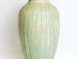 a green vase that is sitting on a white surface