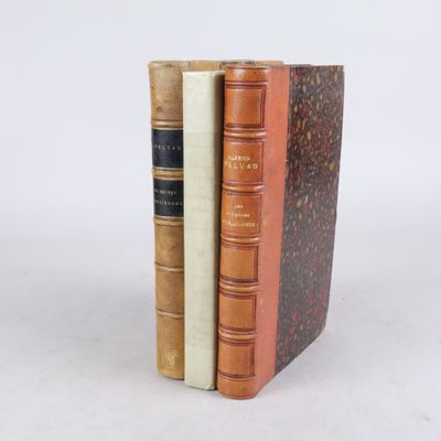 trois livres sont empilés sur une surface blanche