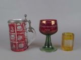 three different colored glasses and a mug on a table