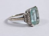 a close up of a ring on a white surface with a green stone