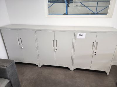 a white cabinet in the corner of a room with a window above it