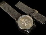 silver watch with black mesh strap on a black background