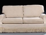 a white couch with fringes on it in a dark room