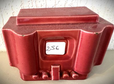 un vase rouge avec une étiquette dessus, posé sur une table