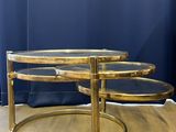 a pair of brass coffee tables with glass tops on a wooden floor