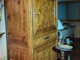 a tall wooden cabinet in a living room next to a table