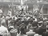 black and white photograph of a crowd of people standing in front of a building