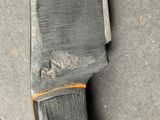 a knife that is laying on the ground next to a piece of wood