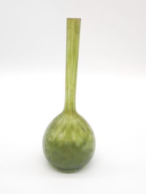 un vase vert posé sur une surface blanche