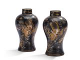 une paire de vases noirs et dorés posés sur une surface blanche
