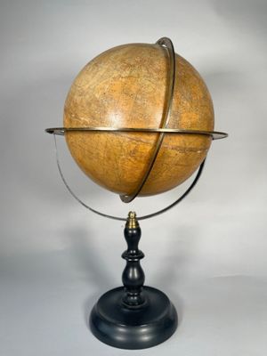 un gros plan d'un globe terrestre en bois posé sur un socle, sur fond blanc