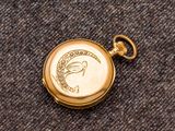 une image représentant une montre de poche en or sur laquelle figure un oiseau